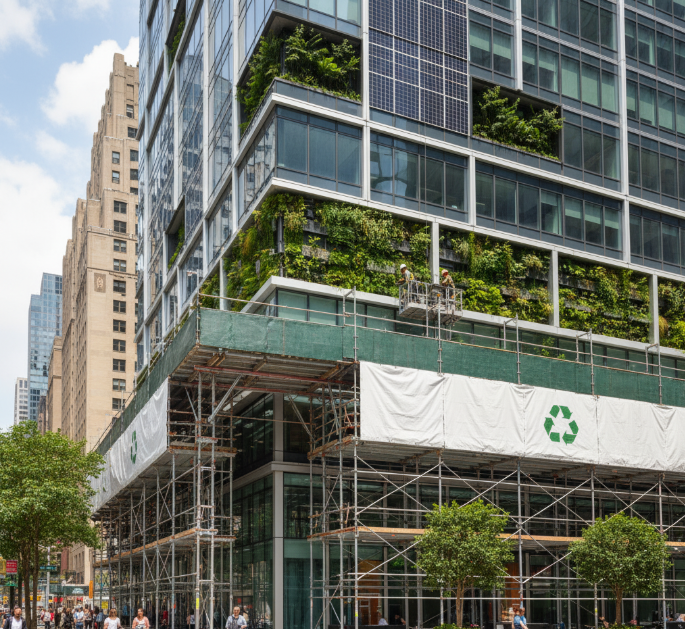 Modern eco-friendly building with vertical garden facade and scaffolding during maintenance work